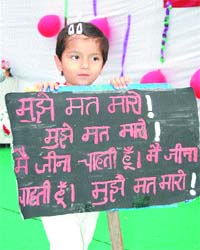 A school kid holds a placard with an anti-foeticide slogan during the annual function at Janak Joshi SD Public School in Jalandhar