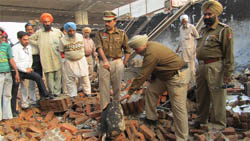 Police personnel examining the site of the blast at a motor repair workshop on Friday. 
