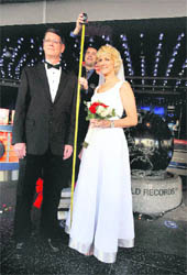 A Guinness official measures Wayne and Laurie Hallquist at a Guinness World Records ceremony announcing them as the tallest couple to wed at the Guinness Museum in Los Angeles on Thursday. Wayne is 6 11 and Laurie measures 6 5. 