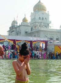 A girl takes a dip in the Bangla Sahib Gurdwara sarovar in Delhi on the occasion of Guru Nanaks birth anniversary