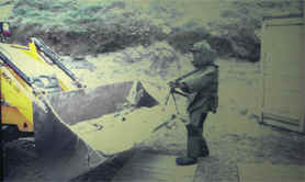A sapper in bomb-protection suit handles scrap ammunition for disposal near Ludhiana