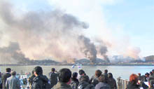 People look as smoke rises from the South Korean Yeonpyeong Island after it was hit by dozens of artillery shells on Tuesday.