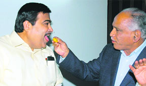 BJP president Nitin Gadkari and Karnataka Chief Minister BS Yeddurappa exchange sweets after the party leadership announced that the latter will continue in office, in New Delhi on Wednesday.