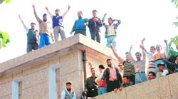 Daily wage workers of the PDD lodge a protest atop the Janipur Grid Station in Jammu on Wednesday.