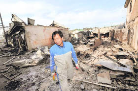 A South Korean resident walks by destroyed houses on Yeonpyeong island, South Korea, on Wednesday.