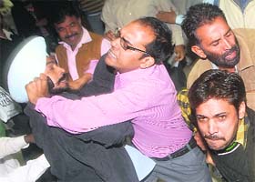 A protester grapples with an organiser during the melee at a seminar at Kisan Bhavan in Chandigarh