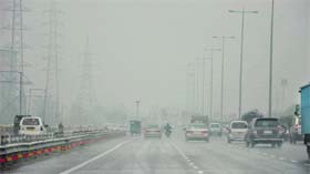 Vehicles move cautiously on the Delhi-Jaipur National Highway in Gurgaon amidst dense fog