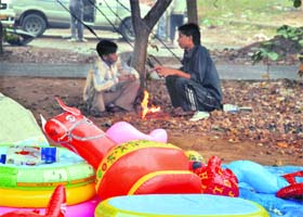 Toy sellers light bonfire to keep themselves warm as mercury dips following a spell of rain in Gurgaon