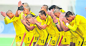Malaysian players pray prior to the match against Pakistan. The team shaved their heads to ward off evil spirits after they won against India in the semifinal.