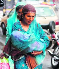 A woman covers her baby with her dupatta to protect him from rain in Jammu. 