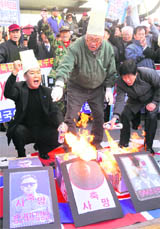 DAMNING: Anti-North Korean protesters burn the portraits of (Norths) leader Kim Jong Il and his son Kim Jong Un during a protest in Seoul on Friday. 