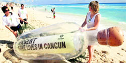 Activists of Oxfam carry a giant bottle on the shores of a beach in Cancun on Sunday. The bottle contains a message reading "Urgent: Save Lives in Cancun," in reference to millions of world's poorest people.