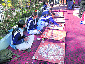 Students display their skills in making aipan on Monday.