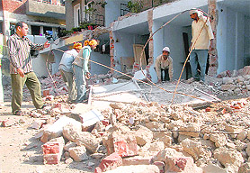 Workers remove debris from the demolition site in Sector 45, Chandigarh, on Tuesday. Tribune photo: Vinay Malik