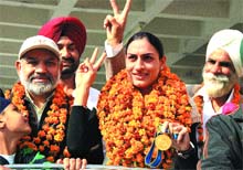 Manjit Kaur, who won a gold medal at the Asian Games, accompanied by relatives and sports officials, shows a victory sign after reaching Jalandhar on Tuesday. 