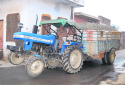 A tractor-trailer overloaded with construction material.