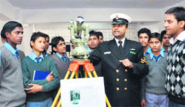 A Navy officer explains a naval equipment to students at an exhibition.
