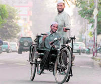 Two differently abled persons help each other pulling their rickshaw on a road in Dehradun.