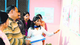 A student explains her painting to a faculty member at a painting-cum-poster exhibition in Shravannath Math Jawaharlal Nehru College in Haridwar on Thursday.