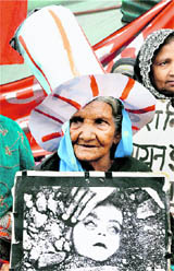 A survivor of Bhopal gas tragedy holds a placard during a demonstration on the eve of the 26th anniversary of the accident, in Bhopal on Thursday.