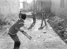 Children play cricket on a vacant plot at Baltana.