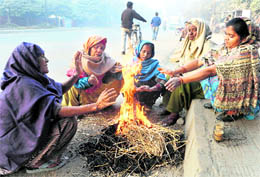 Safai karamcharis warm themselves as they sit around a bonfire on a roadside in Amritsar
