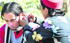 A youth gets his ear cleaned at the Gandhi Park in Dehradun on Saturday.
