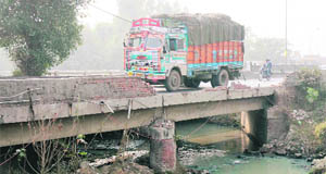Vehicles move cautiously on a dilapidated bridge over a drain on the national highway-1, near Namaste Chowk, in Karnal.