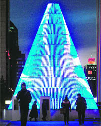 Pedestrians walk past a neon-lit Christmas tree at twilight in Beijing on Monday.