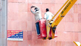 Workers drill holes for screws in an outer wall of the Mini-secretariat on Tuesday.