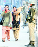 Two women busy talking on mobile phones get past security personnel in Srinagar. 