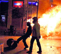 A protester kicks a bin as a kiosk burns during a student protest to mark two years since the fatal police shooting of a teenage boy that sparked Greece's worst riots in decades, in Athens on Monday