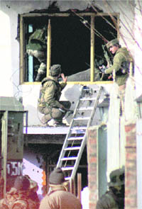 Army and Special Operations Group of Police personnel enter the house where a militant was holed up during an encounter in Sopore on Wednesday.