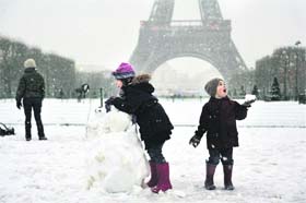 Children enjoy the snow in front of the Eiffel Tower on Thursday. Unusually heavy snowfall and below-zero temperatures continued in northern France with Paris receiving over four inches of snow, its most since 1987