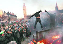 Demonstrators jump off a burning park bench during a protest outside Parliament in Westminster, central London, on Thursday.
