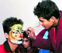 A student of Childrens Academy paints on the face of a student in Dehradun on Saturday