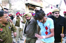 Police personnel cane charge and round up a youth during a clash at Dhilwan village in Jalandhar