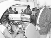 A youth tries his hands at a simulator as Deputy Commissioner Dipinder Singh looks on at a driving school in Patiala 
