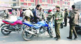 Policemen check the registration papers of motorcyclists to track vehicles used by those indulging in stone throwing in Srinagar on Monday. 