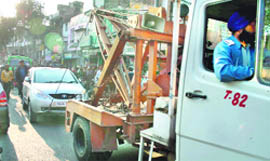 A traffic police recovery van tows away a car parked in the no-parking zone in Jammu. 