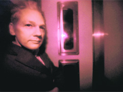 Julian Assange is pictured through the heavily tinted windows of a police vehicle as he arrives at Westminster magistrates court in London on Tuesday. 