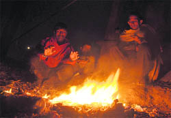 Labourers gather around a bonfire to keep themselves warm on a cold winter night in Ludhiana