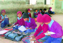 Schoolchildren sit on the floor in a government school in Fatehgarh Sahib on Wednesday