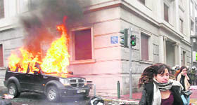 Protesters run away from a burning car during clashes in Athens on Wednesday.