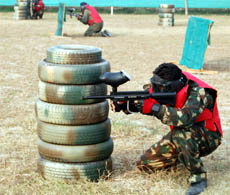 A player defends himself behind a pile of old tyres during a paintball game at the K-5 security training ground on the Tarn Taran road in Amritsar.