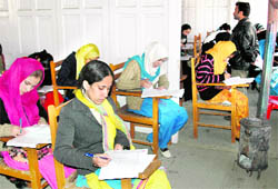 In bone-chilling cold, girl students take an exam in Srinagar sitting in a schoolroom that has only a coal bukhari in the name of heating arrangements