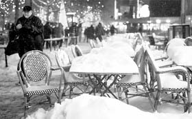 People walk past snow-covered chairs and tables at a restaurant in Berlin on Friday. Large parts of Europe have seen heavy snowfall leading to widespread disruptions and school closures in many countries.
