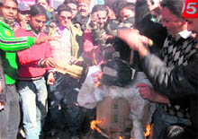 Traders association members and students burn an effigy of the Mussoorie police