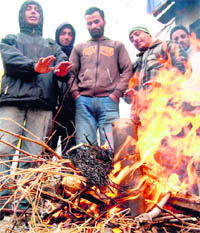 Residents warm themselves at a roadside in Srinagar on Sunday. The mercury dipped to - 5.6 C in the city on Saturday night