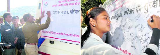 A policeman signs a poster of the safety campaign launched by 108 Emergency Service in Pitthoragarh on Monday; and (right) a girl pens down her remarks during a similar campaign in Dehradun.